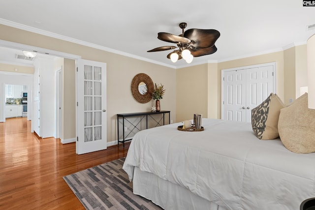 bedroom with visible vents, a closet, ornamental molding, and wood finished floors