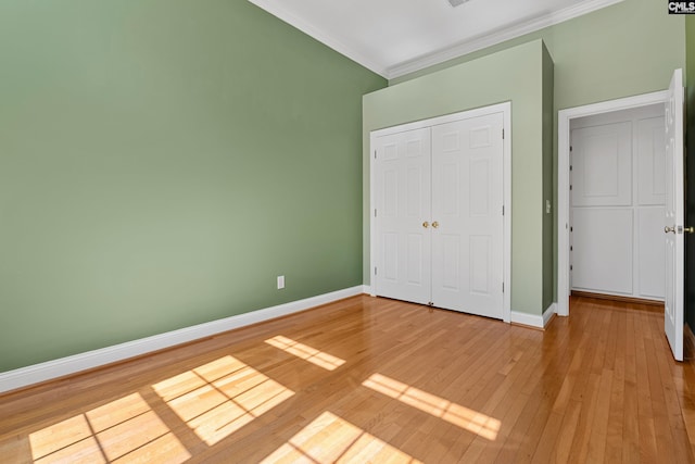 unfurnished bedroom featuring hardwood / wood-style flooring, baseboards, ornamental molding, and a closet