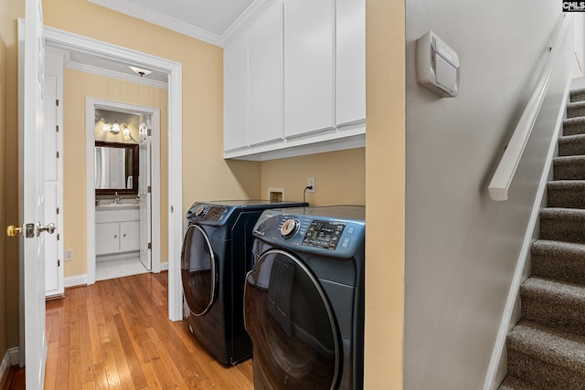 clothes washing area with separate washer and dryer, a sink, cabinet space, light wood finished floors, and crown molding
