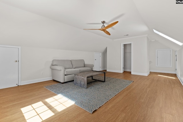 living room with vaulted ceiling with skylight, baseboards, ceiling fan, and wood finished floors