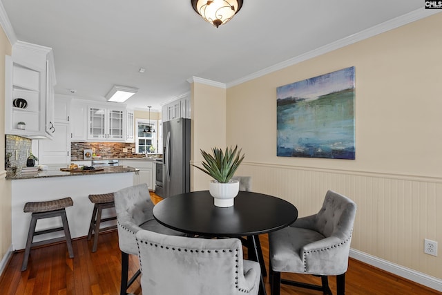 dining room featuring ornamental molding, wainscoting, and hardwood / wood-style flooring