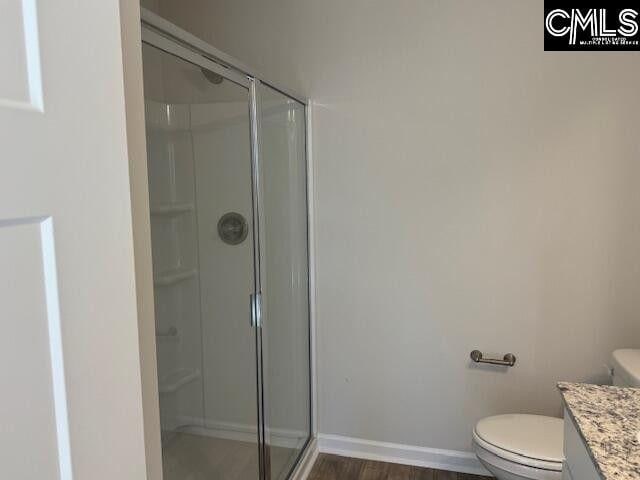 full bath featuring toilet, a stall shower, baseboards, and vanity