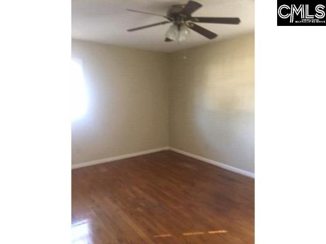 empty room featuring a ceiling fan, baseboards, and wood finished floors