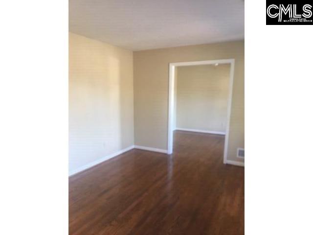 unfurnished room with dark wood-style flooring and baseboards