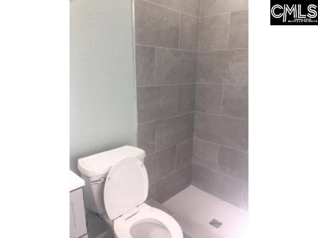 full bathroom featuring a tile shower and toilet