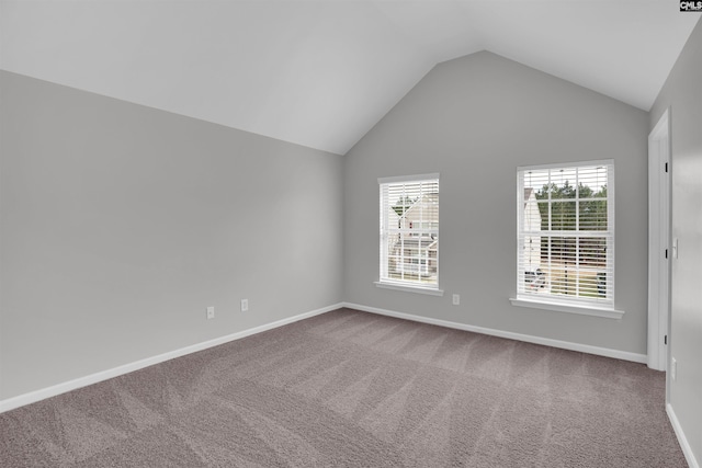 spare room featuring carpet floors, baseboards, and vaulted ceiling