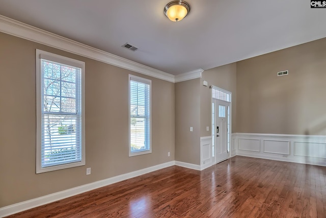 empty room with visible vents, dark wood-style floors, and crown molding