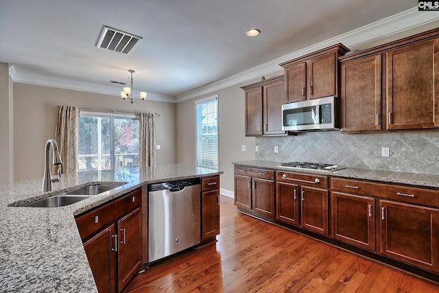 kitchen with visible vents, ornamental molding, a sink, wood finished floors, and stainless steel appliances