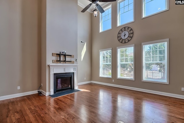 unfurnished living room with a glass covered fireplace, baseboards, and wood finished floors