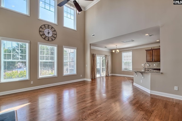 unfurnished living room with baseboards, wood finished floors, and ornamental molding