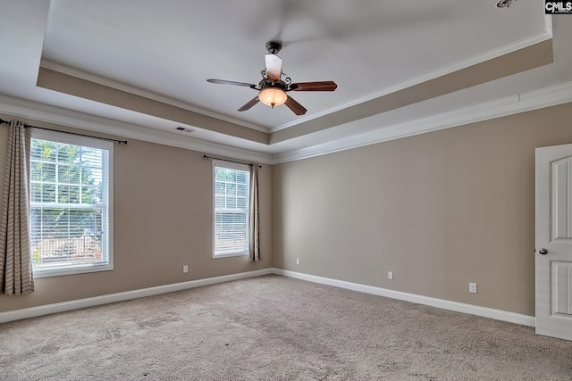 carpeted spare room with ceiling fan, a raised ceiling, baseboards, and ornamental molding