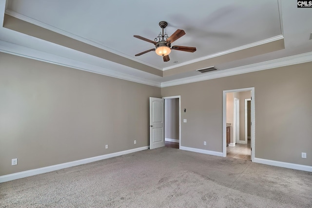 unfurnished bedroom with visible vents, light carpet, ornamental molding, a tray ceiling, and baseboards