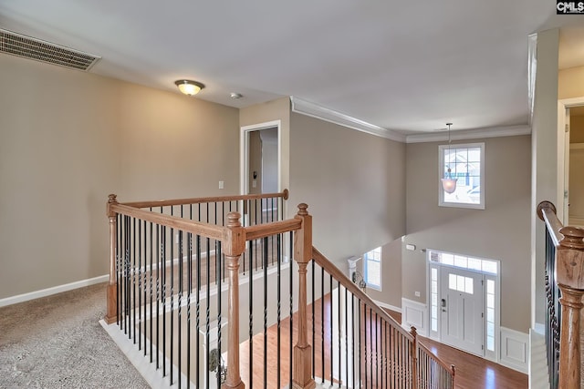 hall featuring visible vents, an upstairs landing, baseboards, and crown molding