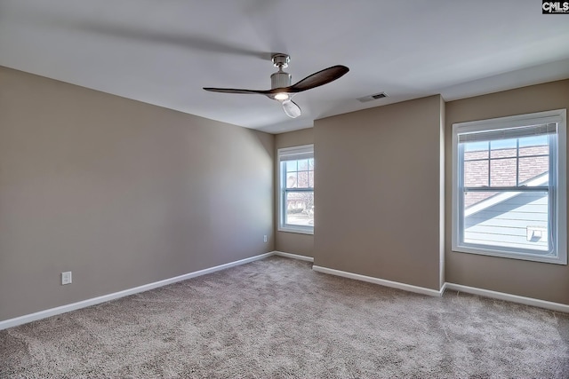 carpeted empty room with visible vents, baseboards, and a ceiling fan