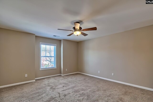 carpeted spare room featuring visible vents, baseboards, and ceiling fan