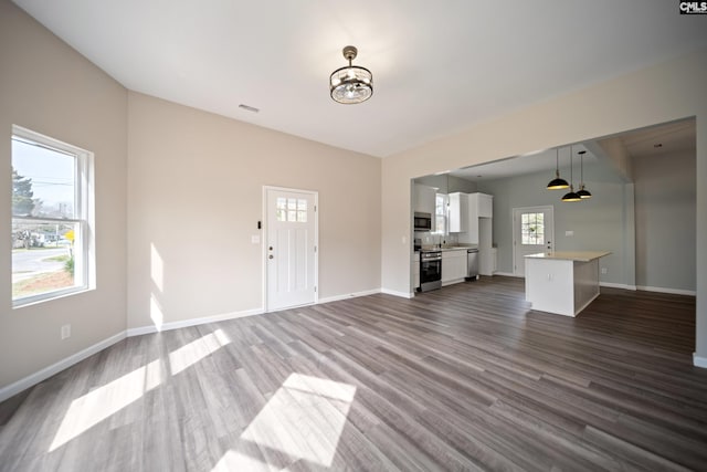 unfurnished living room featuring a sink, visible vents, baseboards, and dark wood-type flooring