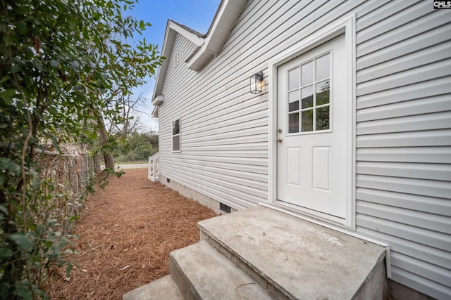 view of exterior entry with crawl space and fence