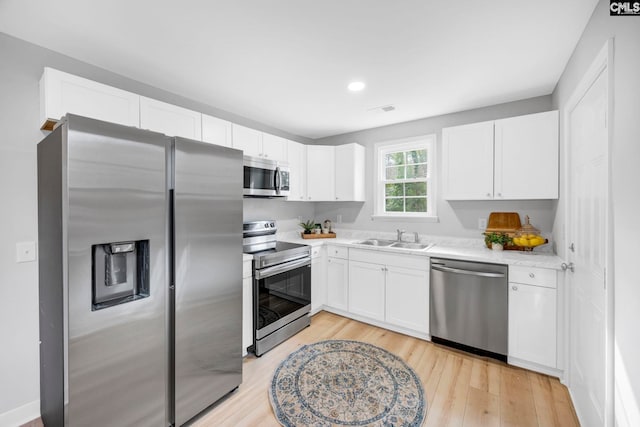 kitchen with stainless steel appliances, light countertops, a sink, and white cabinetry