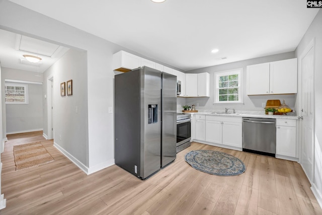 kitchen with stainless steel appliances, a sink, light countertops, and white cabinets