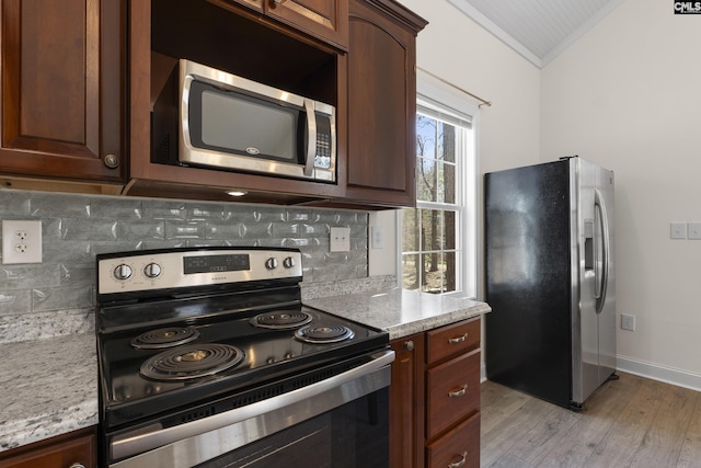 kitchen featuring lofted ceiling, light wood-style flooring, stainless steel appliances, baseboards, and decorative backsplash