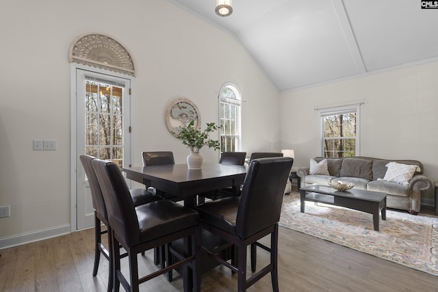 dining area with high vaulted ceiling, hardwood / wood-style flooring, and baseboards