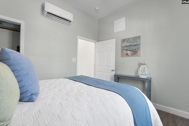 bedroom with a wall unit AC, baseboards, and wood finished floors