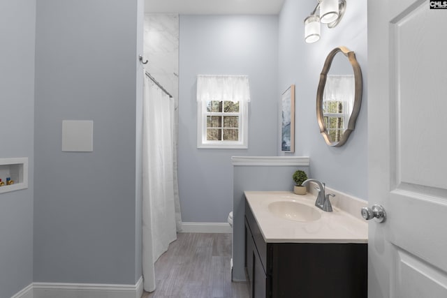 bathroom featuring baseboards, toilet, a shower with curtain, wood finished floors, and vanity