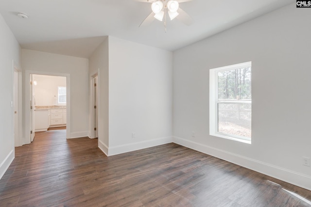 unfurnished room with a ceiling fan, baseboards, and dark wood-style flooring