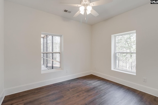 unfurnished room with dark wood-type flooring, plenty of natural light, visible vents, and baseboards