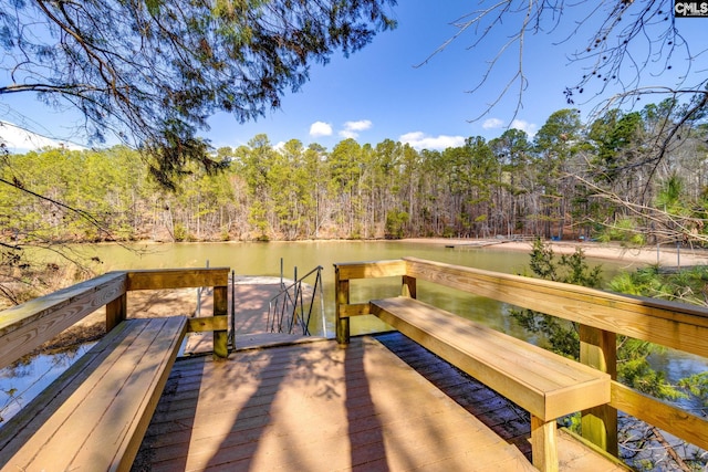 view of dock with a water view and a wooded view