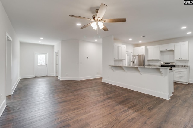 kitchen featuring stainless steel appliances, dark wood-style flooring, a peninsula, and a kitchen bar