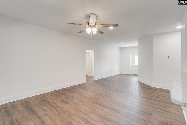 empty room featuring ceiling fan, baseboards, wood finished floors, and recessed lighting