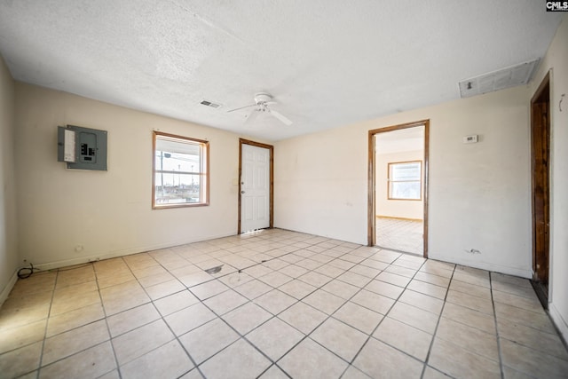 spare room featuring visible vents, ceiling fan, a textured ceiling, and electric panel