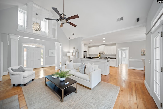 living room featuring high vaulted ceiling, a wealth of natural light, visible vents, and ornate columns