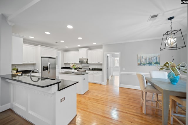 kitchen with a peninsula, appliances with stainless steel finishes, tasteful backsplash, dark countertops, and crown molding