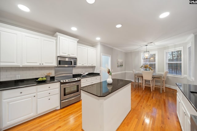 kitchen featuring light wood finished floors, stainless steel appliances, dark countertops, tasteful backsplash, and white cabinetry