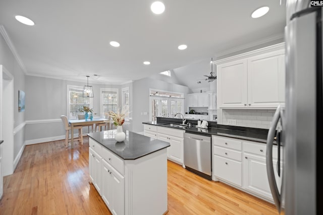 kitchen with stainless steel appliances, dark countertops, a sink, and light wood-style floors