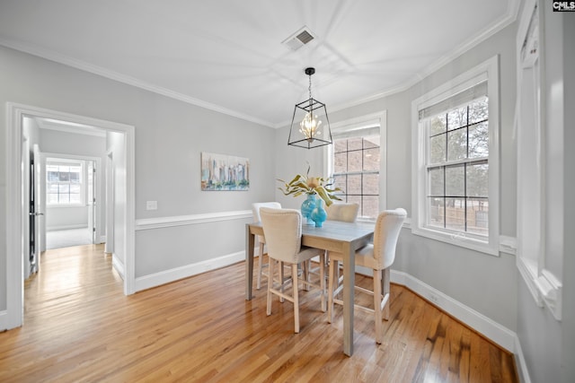 dining area with light wood-type flooring, visible vents, crown molding, and baseboards