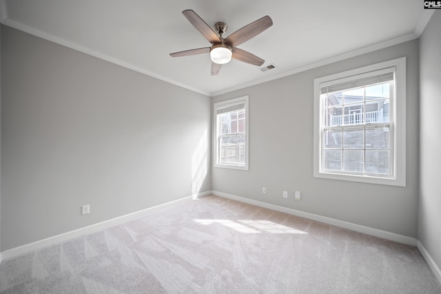 spare room with light carpet, visible vents, baseboards, a ceiling fan, and crown molding