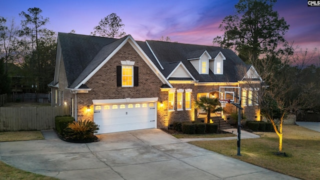 view of front facade with brick siding, concrete driveway, fence, a garage, and a front lawn