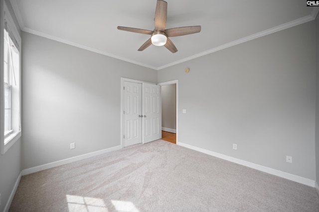 carpeted spare room featuring crown molding, a ceiling fan, and baseboards