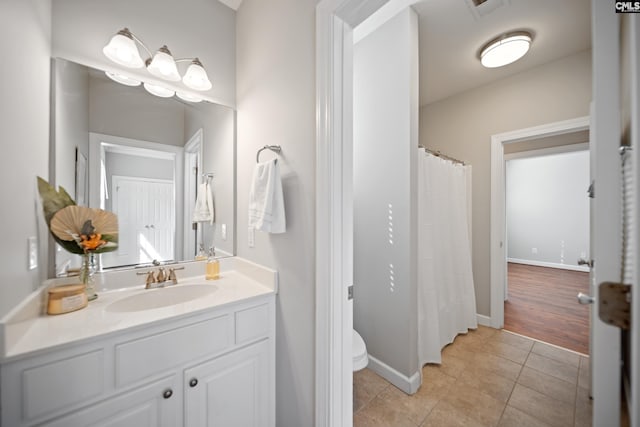 bathroom featuring toilet, tile patterned flooring, baseboards, and vanity