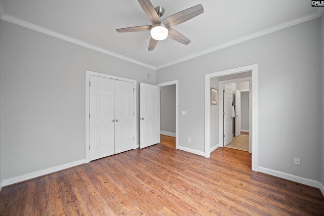 unfurnished bedroom with baseboards, a ceiling fan, wood finished floors, crown molding, and a closet