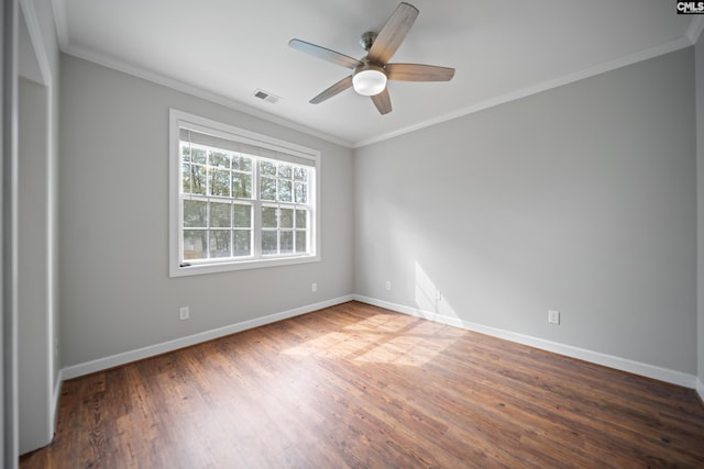 empty room featuring baseboards, visible vents, crown molding, and wood finished floors