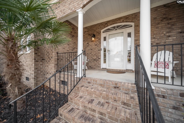 entrance to property featuring brick siding, crawl space, and a porch