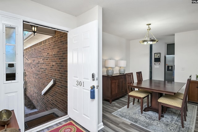 dining space with brick wall and wood finished floors