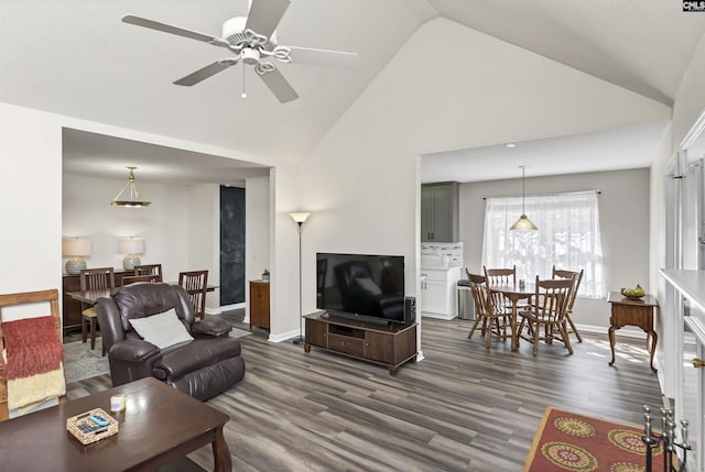 living room featuring ceiling fan, high vaulted ceiling, dark wood finished floors, and baseboards