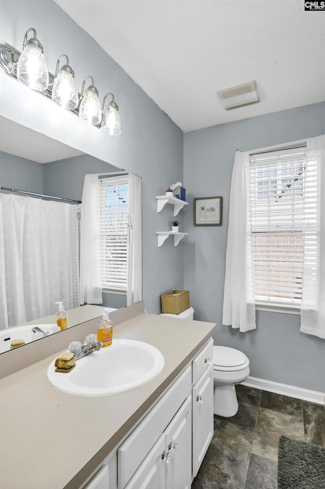 full bath with baseboards, plenty of natural light, vanity, and toilet