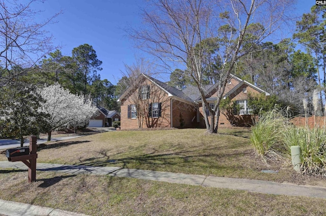 view of front of property with a front yard, brick siding, and an attached garage