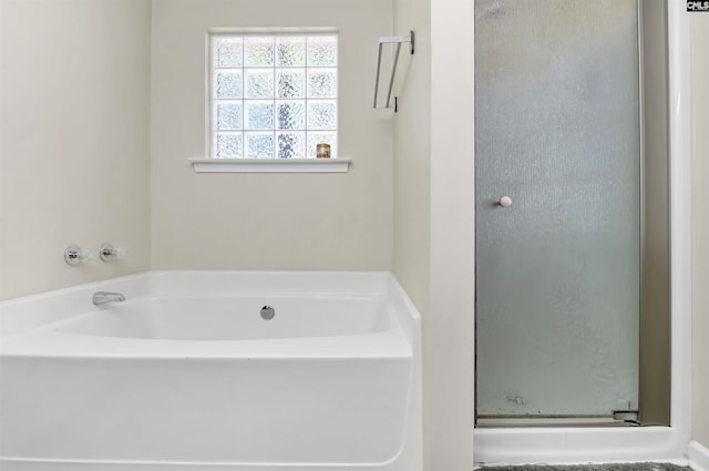 bathroom featuring a garden tub and a shower stall